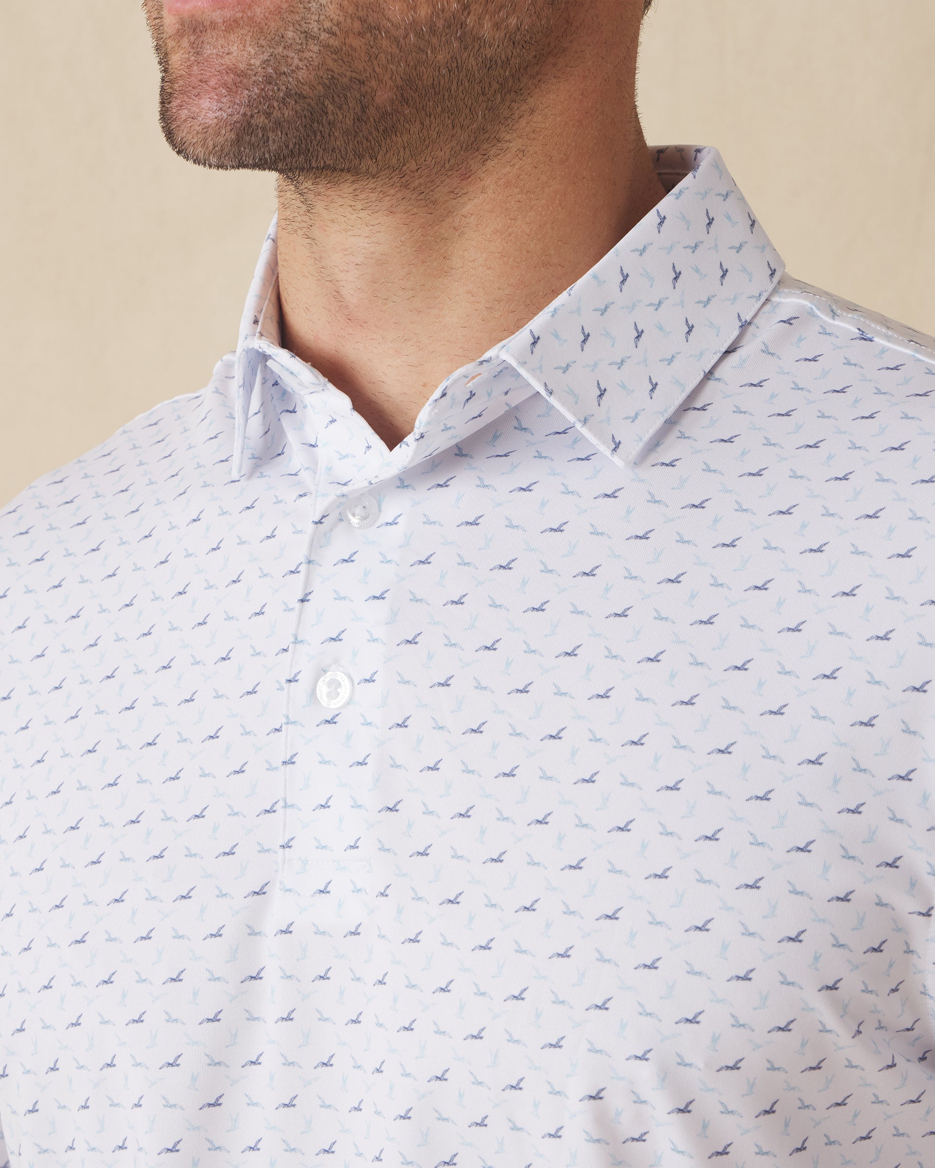 Men's Livingston Polo in White, close-up front view on model highlighting the scattered navy and light blue seagull print on a white base