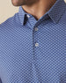 Close-up of blue polo collar and placket with geometric floral pattern and button detail
