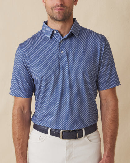 Men’s blue Florian Polo with small geometric floral print, short sleeve, worn tucked into light pants