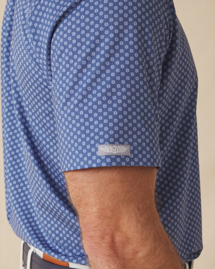 Close-up of polo sleeve with subtle logo tab and geometric floral pattern