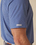 Close-up of polo sleeve with subtle logo tab and geometric floral pattern