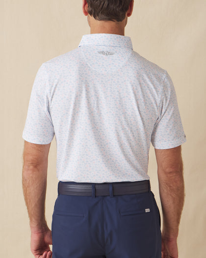 Men's Turtle Island Polo in Coastal, back model view featuring a white short sleeve polo with an allover sea turtle and coral print in light blue and pink tones, with a Straight Down logo at the back collar