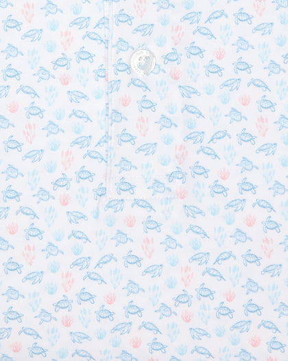 Men's Turtle Island Polo in Coastal, close-up fabric detail view featuring an allover sea turtle and coral print in light blue and pink tones on a white performance fabric