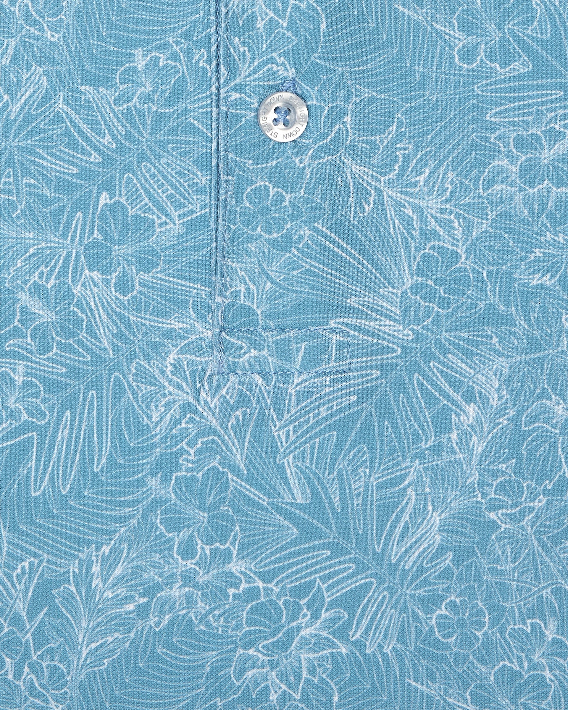 Men's Ka'anapali Polo in Coastal, close-up fabric detail view featuring an allover white tropical floral and palm leaf line-art print on a medium blue performance fabric