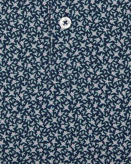 Men's Redbud Polo in New Indigo, close-up detail view featuring navy base with scattered green and light pink floral print and Straight Down logo engraved button with placket detail