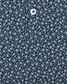Men's Redbud Polo in New Indigo, close-up detail view featuring navy base with scattered green and light pink floral print and Straight Down logo engraved button with placket detail