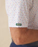 Men's Pimento Cheese Polo in White, close-up sleeve view on model highlighting the Straight Down logo patch on the sleeve hem with a scattered golf, sandwich, and drink print in purple, teal, and orange on a white base