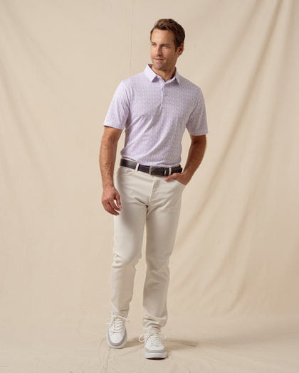 Men’s light pink polo with chili pepper print paired with off-white pants, brown belt, and white sneakers