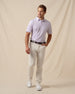 Men’s light pink polo with chili pepper print paired with off-white pants, brown belt, and white sneakers