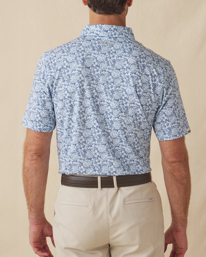 Men's Lihu'e Polo in Sea Spray, back model view featuring a light blue short sleeve polo with an allover navy hibiscus flower and monstera leaf print, with an embroidered Straight Down logo at the back collar
