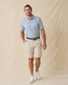 Men's Lihu'e Polo in Sea Spray, full length model view featuring a light blue short sleeve polo with an allover navy hibiscus flower and monstera leaf print, styled with khaki shorts and white shoes