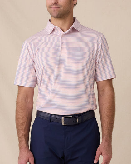 Front view of a male model wearing the Channel Stripe Polo in Seashell tucked into navy pants with a matching navy belt.