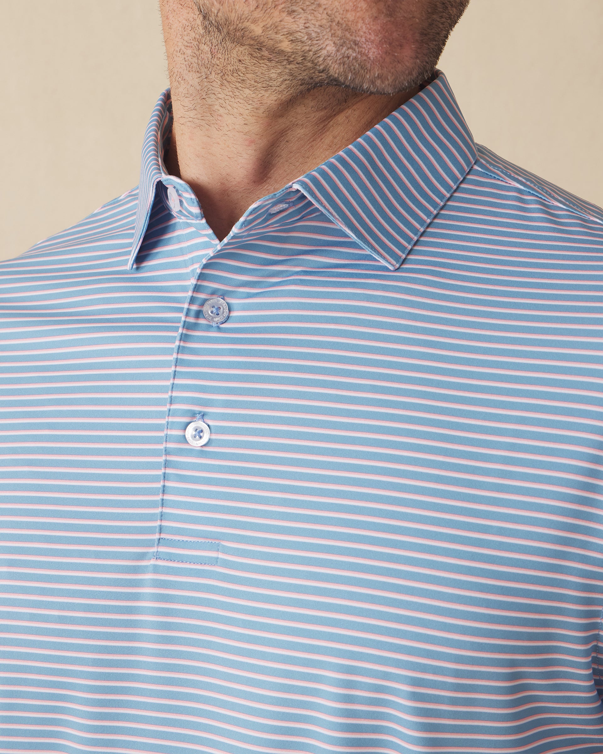 Men's Channel Stripe Polo in Coastal, collar detail view featuring horizontal pink and white stripes on a light blue performance fabric