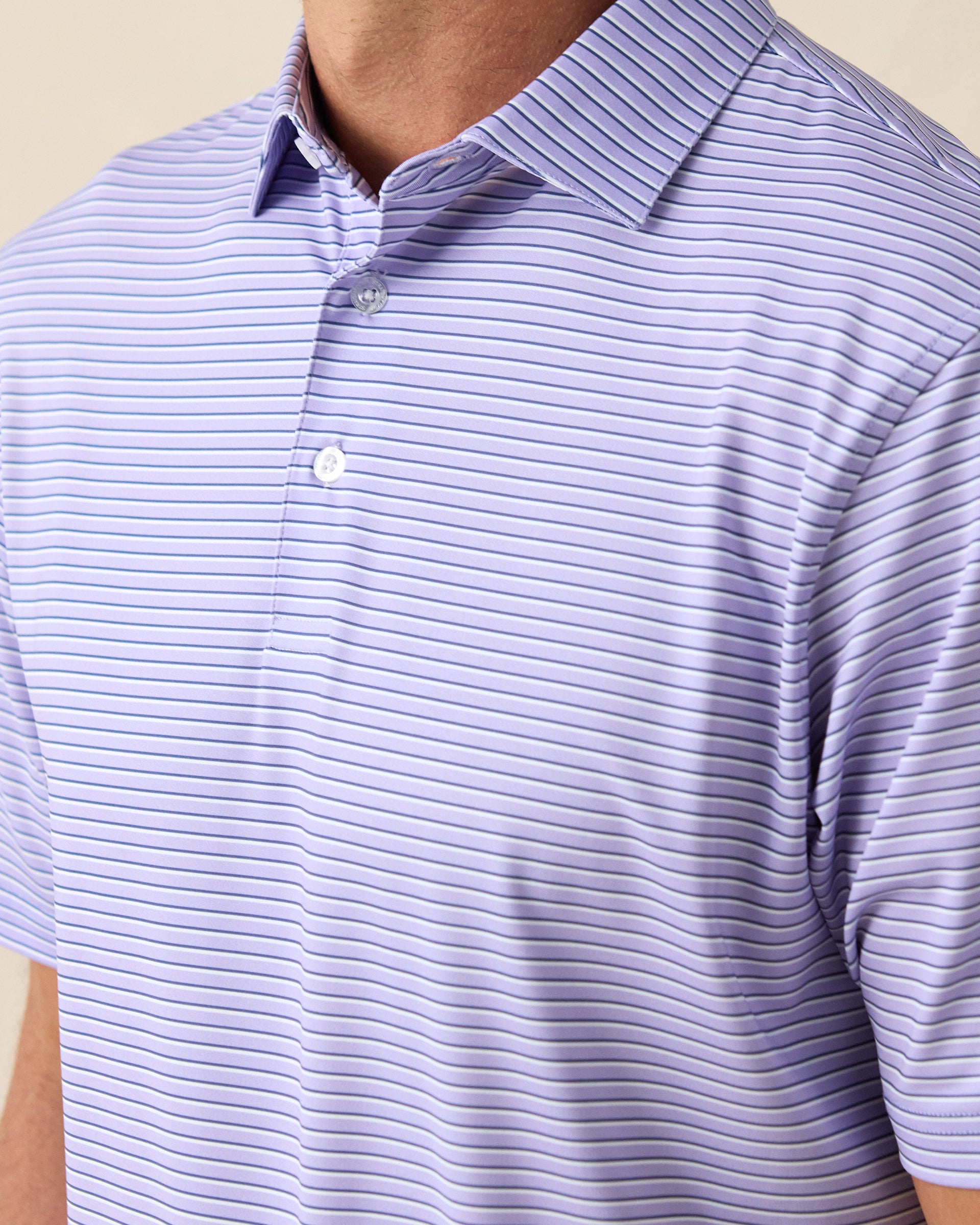 Men's Channel Stripe Polo in Violet, close-up model view featuring the collar and button placket detail of a lavender short sleeve polo with horizontal navy and white pencil stripes