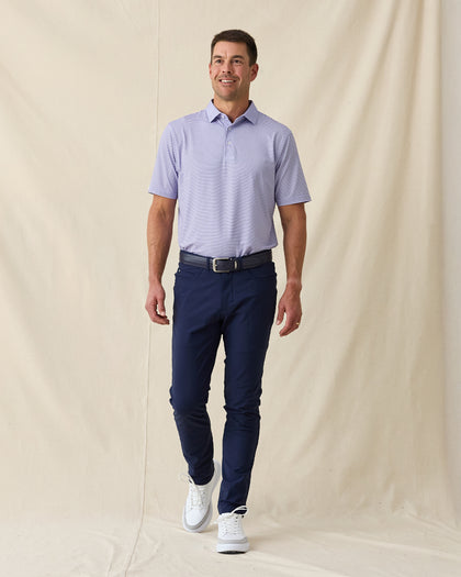 Men's Channel Stripe Polo in Violet, full length model view featuring a lavender short sleeve polo with horizontal navy and white pencil stripes paired with navy pants and white shoes