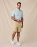 Model wearing the Men's Channel Stripe Golf Polo in Mint Tea with golf shorts and white golf shoes.