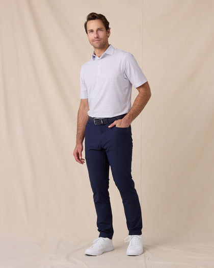 Model wearing the Men's Channel Stripe Golf Polo in White with navy golf pants and white golf shoes.