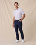 Model wearing the Men's Channel Stripe Golf Polo in White with navy golf pants and white golf shoes.