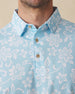 Men's Napali Coast Polo in Gemstone, collar detail view featuring an allover white Hawaiian floral and vine print on a light aqua blue performance fabric with natural wood-tone buttons