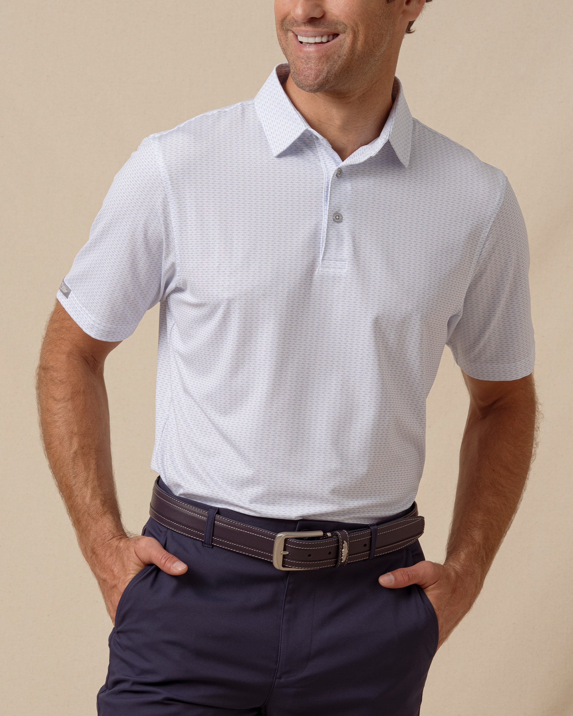 Men’s light blue shark print performance polo paired with navy shorts and a leather belt