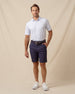 Men’s light blue shark print performance polo styled with navy shorts, belt, and white sneakers
