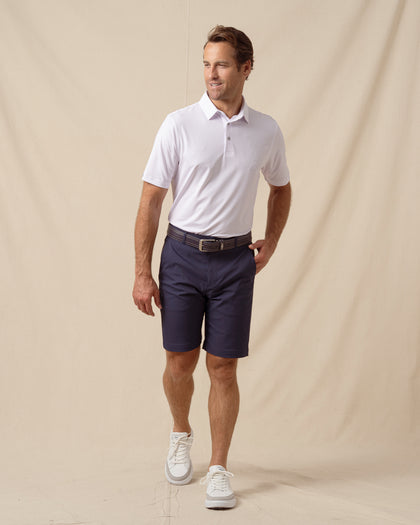 Men’s lilac performance polo with subtle ace-of-spades print styled with navy shorts, belt, and white sneakers