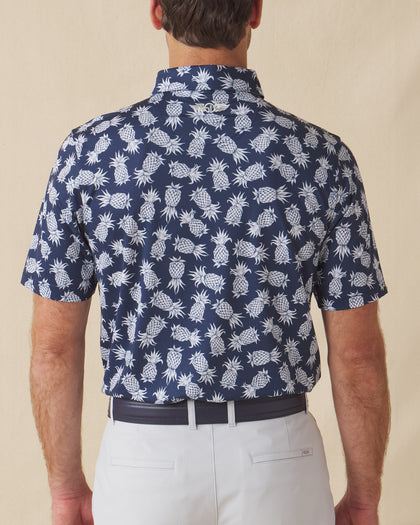 Men's Pineapple Express Polo in New Indigo, back view on model showcasing the navy and white pineapple print with Straight Down logo at the back collar, styled with light grey pants