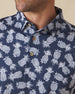 Men's Pineapple Express Polo in New Indigo, close-up detail view of the wood button placket and collar featuring the navy and white pineapple print