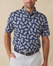 Men's Pineapple Express Polo in New Indigo, front view on model featuring a navy and white pineapple print with wood buttons, styled with light grey pants and a navy belt
