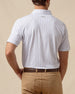 Back view of men’s white geometric print polo shirt paired with tan pants