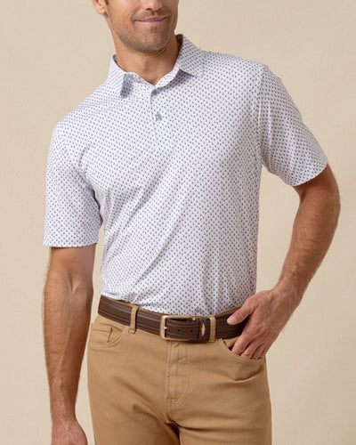 Men’s white polo shirt with small geometric print paired with tan pants and a brown leather belt