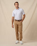 Men’s white geometric print polo shirt styled with tan pants, brown belt, and white sneakers