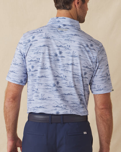 Men's Outrigger Polo in Powder, back view on model showcasing the light blue Hawaiian scenic print with Straight Down logo at the back collar, styled with navy pants