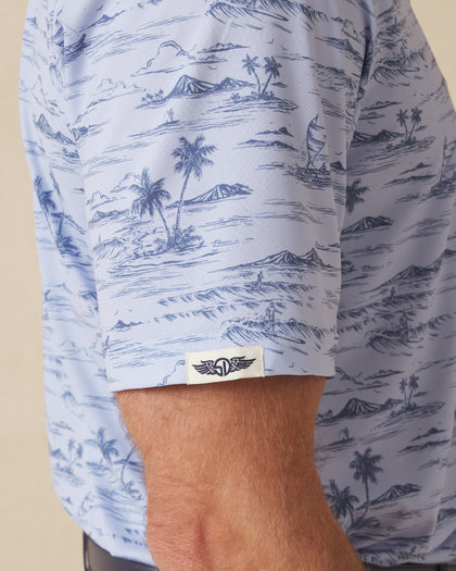 Men's Outrigger Polo in Powder, close-up detail view of the sleeve hem featuring the Straight Down logo label and light blue Hawaiian scenic print