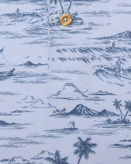 Men's Outrigger Polo in Powder, close-up detail view of the light blue Hawaiian scenic print with wood button
