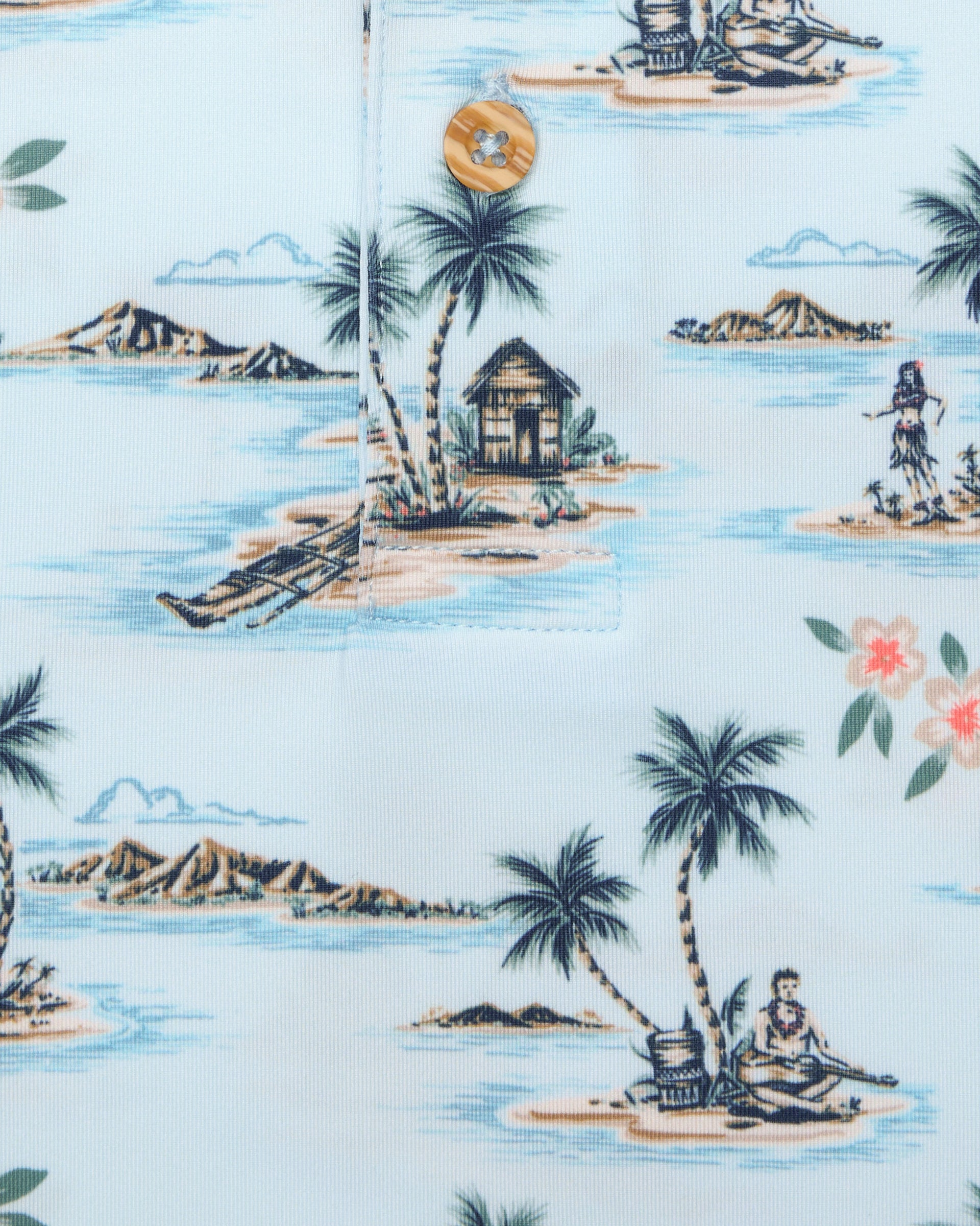Men's Land Of Aloha Polo in Sea Spray, close-up fabric detail view featuring an allover Hawaiian island scene print with palm trees, thatched huts, hula dancers, outrigger canoes, and hibiscus flowers on a light blue performance fabric with a natural wood-tone button