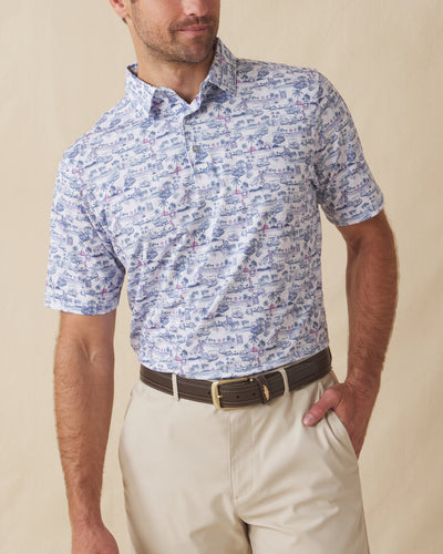 Men’s white polo with blue and pink tropical golf print, worn with beige shorts and brown belt