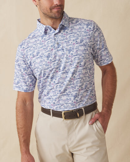Men’s white polo with blue and pink tropical golf print, worn with beige shorts and brown belt