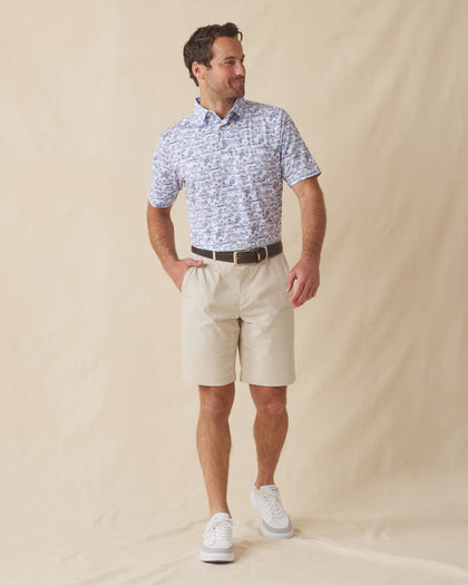 Men’s printed golf polo with beige shorts and white sneakers, styled in a casual warm-weather outfit