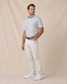 Model wearing the Campus Stripe Polo in Herb with white pants, a brown belt, and white sneakers.