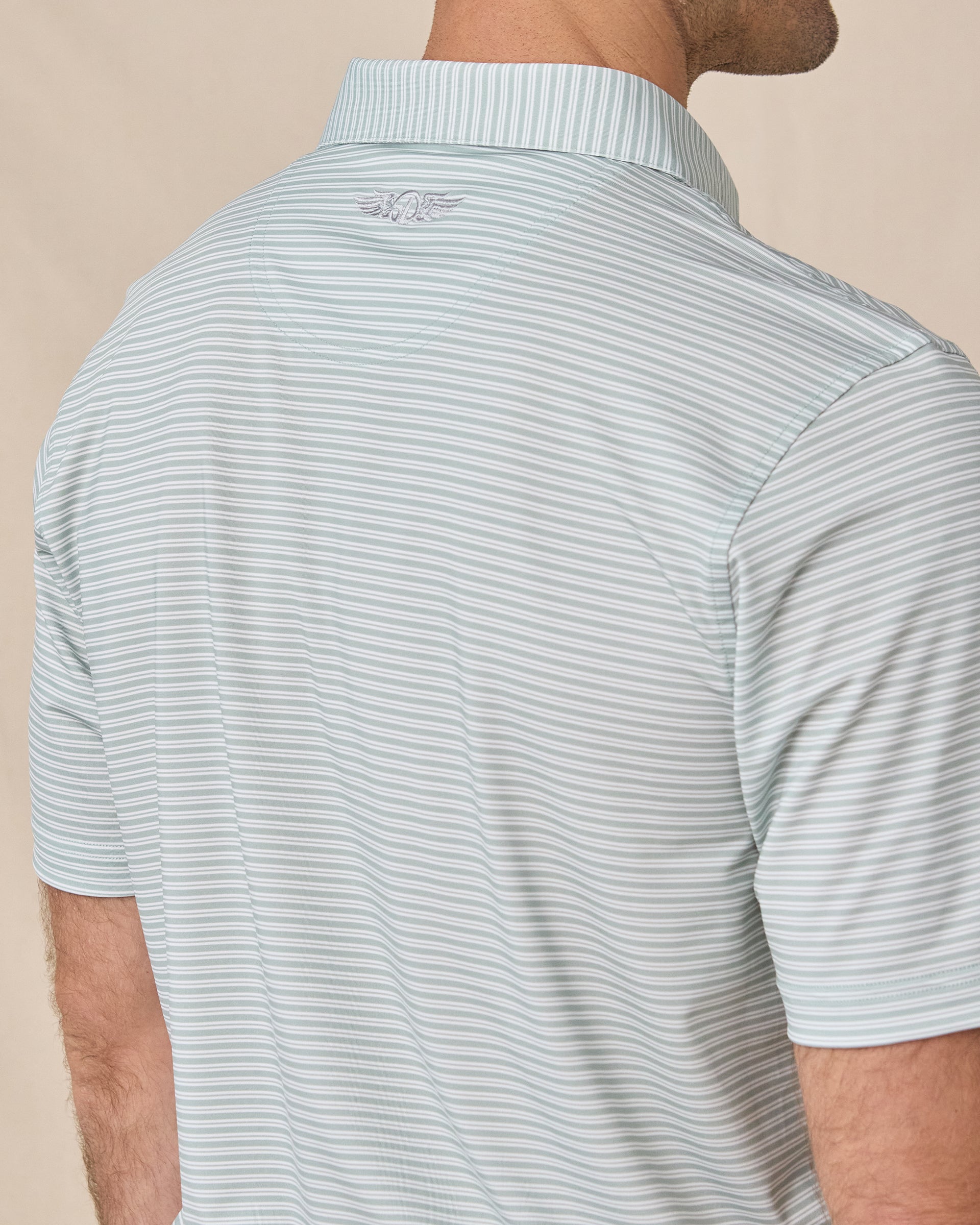 Close-up of the Campus Stripe Polo in Herb showing the striped fabric and embroidered logo below the collar.