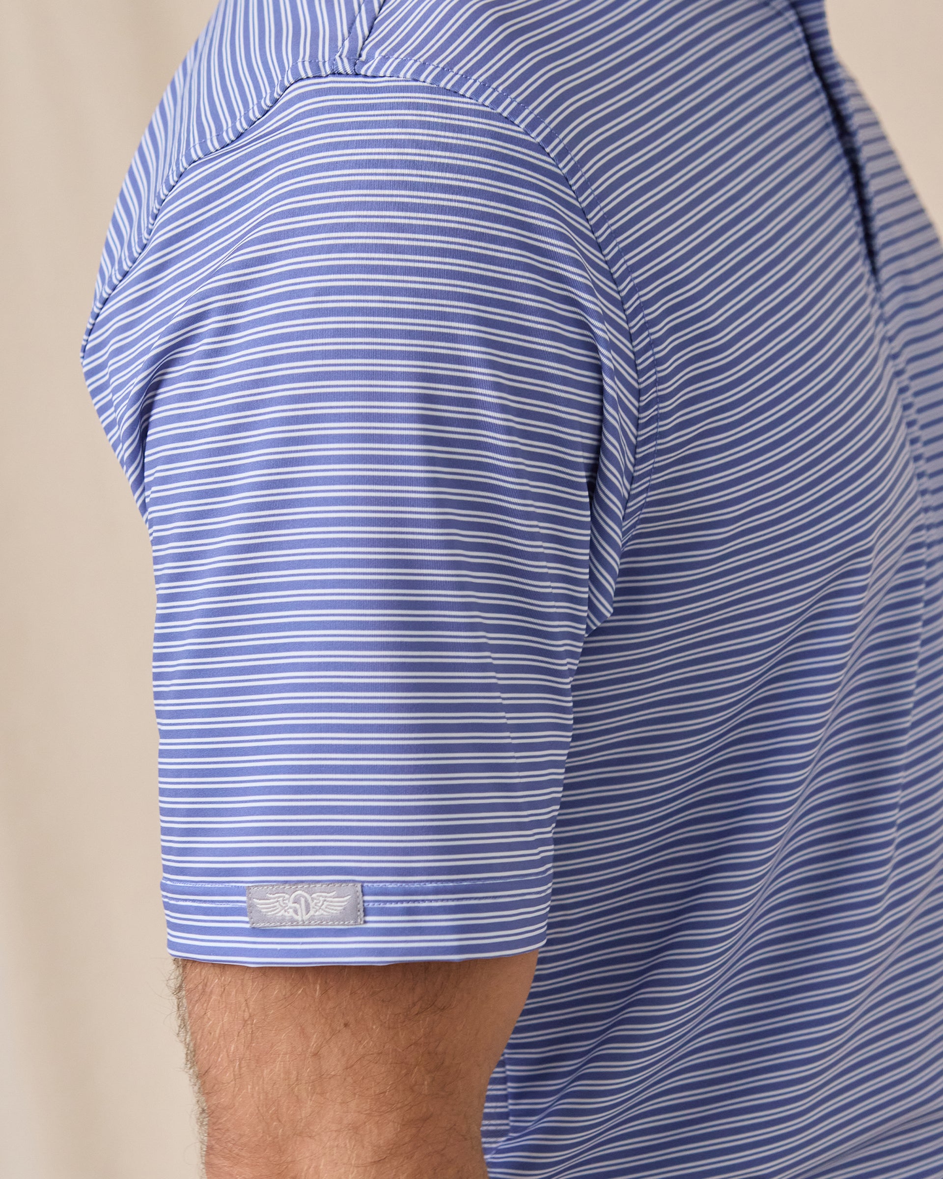 Close-up of the Campus Stripe Polo in Tidal Blue highlighting the striped performance fabric, sleeve construction, and signature sleeve logo tab