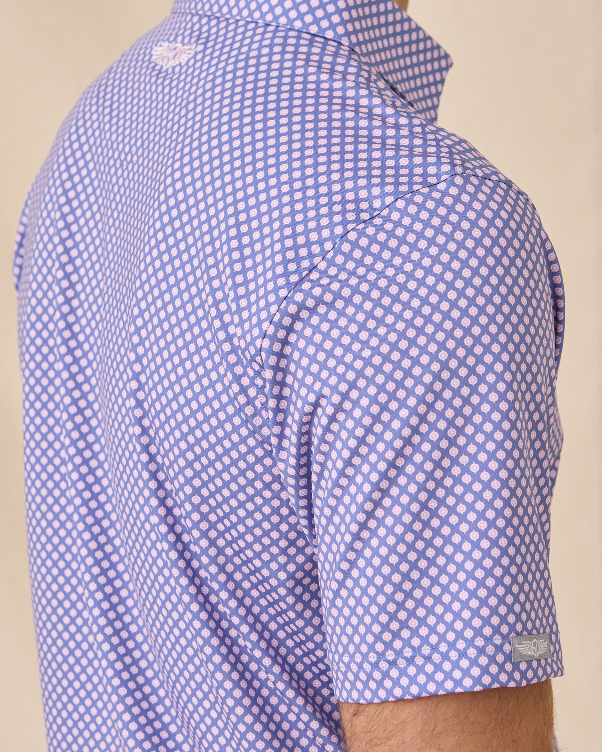Close-up side view of the Ironwood Polo in tidal blue showing the geometric pattern and sleeve logo tab detail