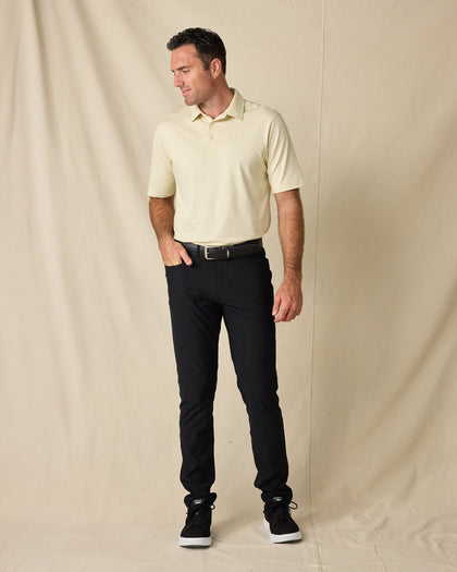 Man modeling the Oxford Polo in Summer Sand with black pants, a black belt, and black sneakers.