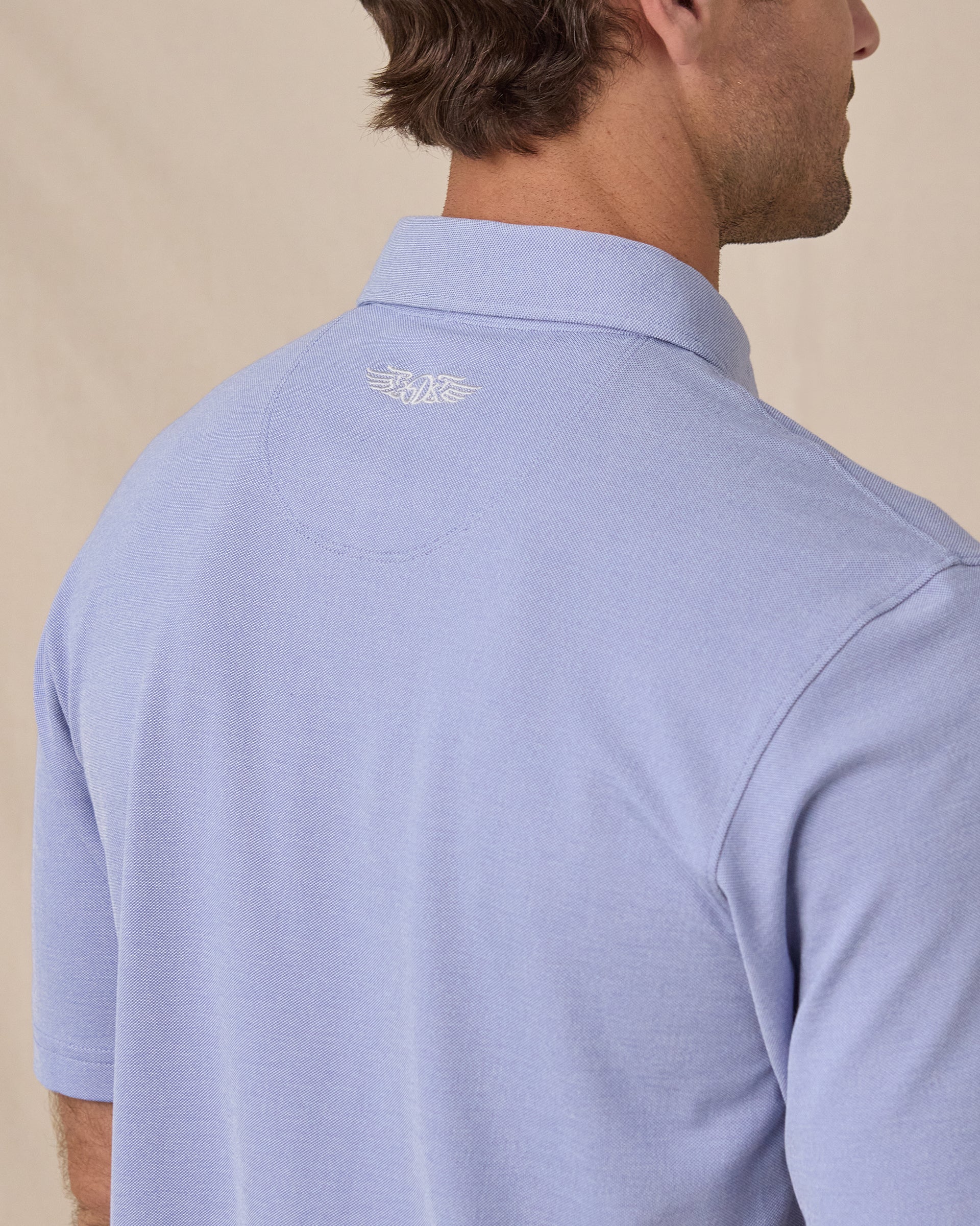 Close-up back view of the Oxford Polo in chambray blue showing the embroidered Straight Down wing logo below the collar