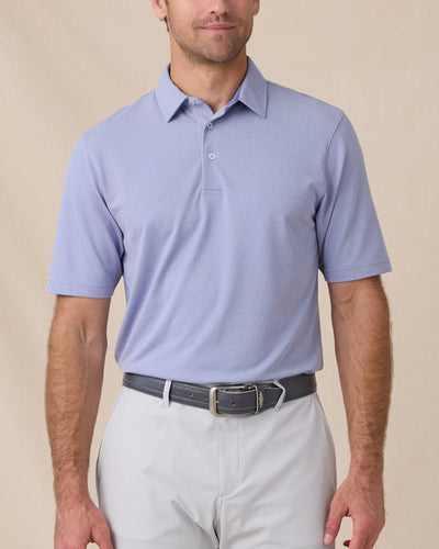 Model wearing the Oxford Polo in chambray blue paired with light gray golf bottoms
