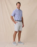 Model wearing the Oxford Polo in chambray blue styled with light gray shorts and golf shoes