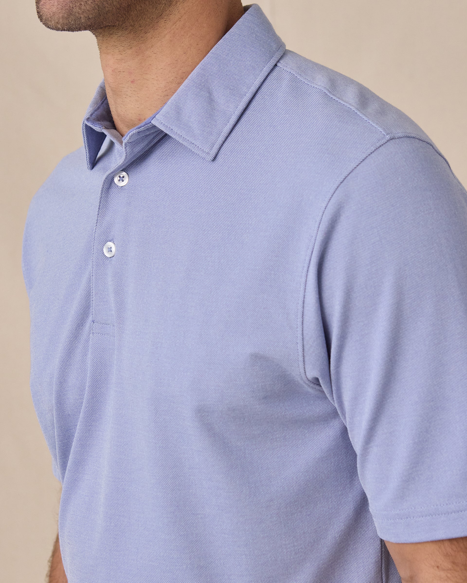 Close-up side view of the Oxford Polo in chambray blue highlighting the textured knit fabric and tailored fit