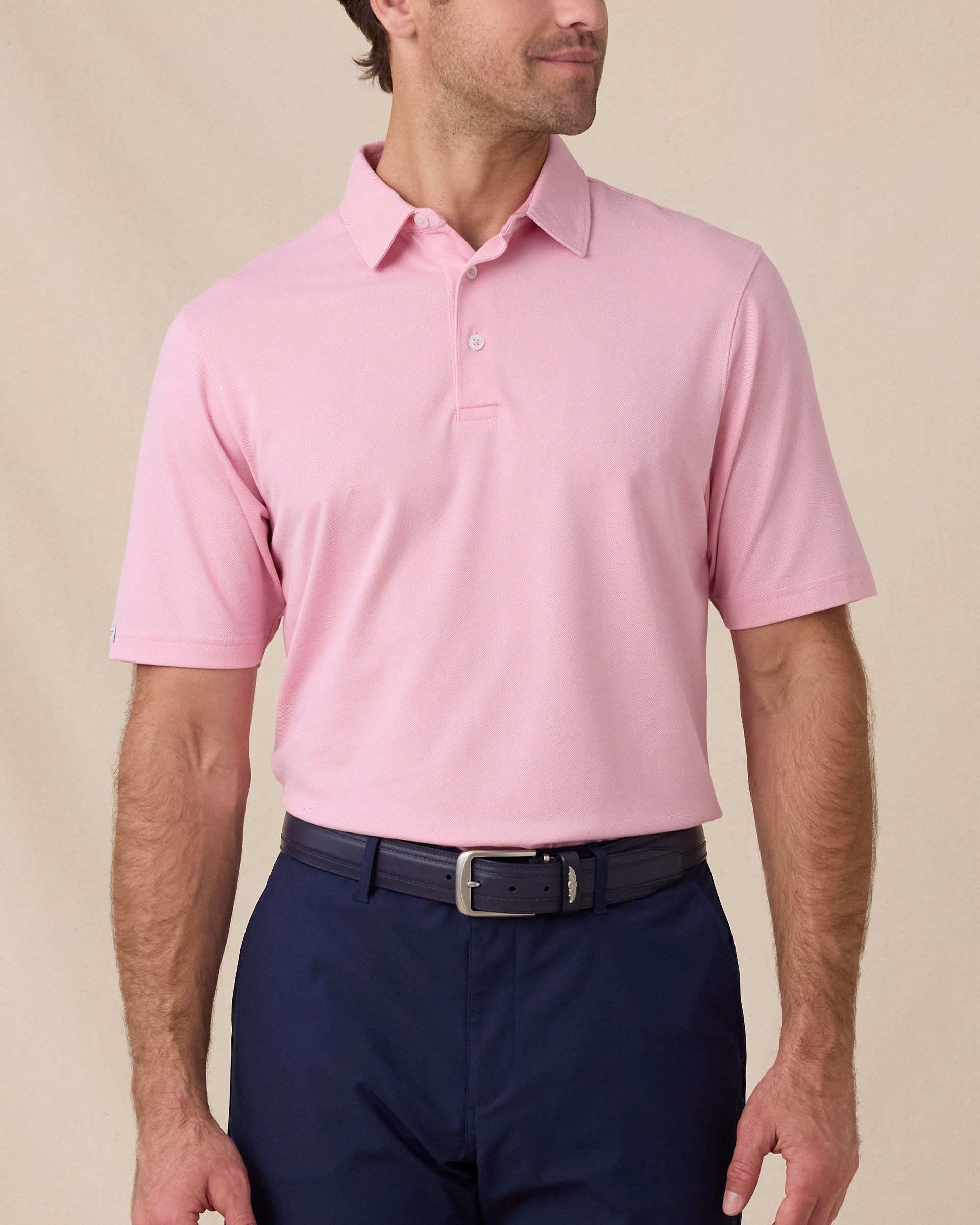 Model wearing the Oxford Polo in punch pink paired with navy bottoms