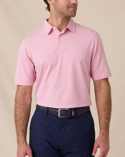 Model wearing the Oxford Polo in punch pink paired with navy bottoms